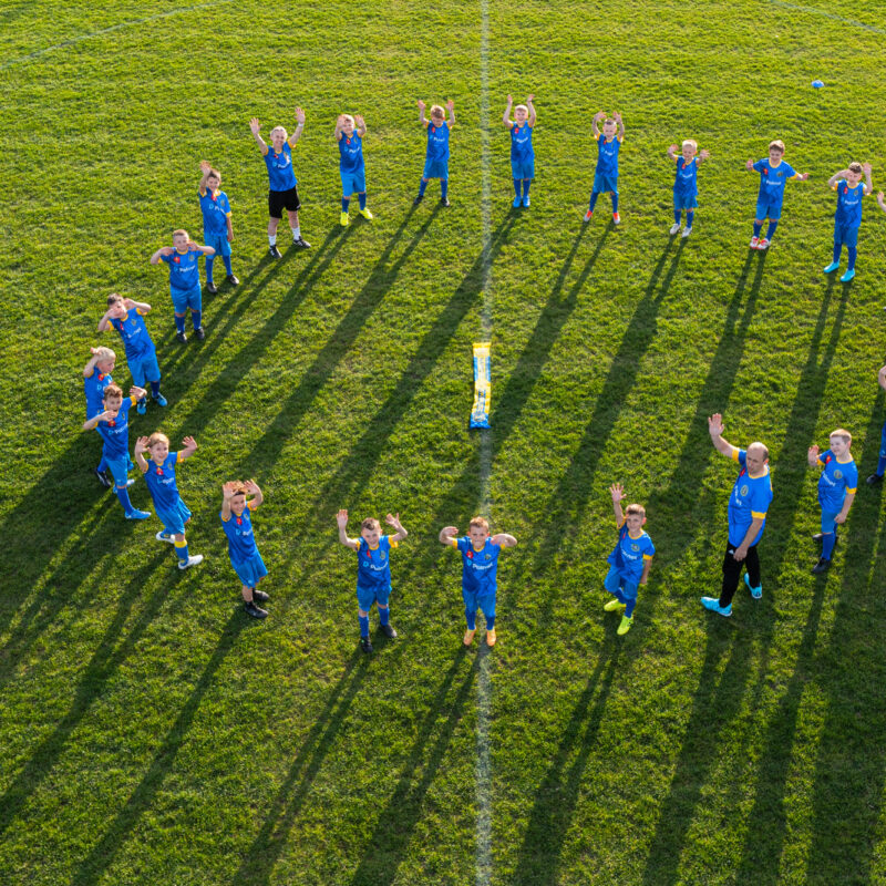 Zespół Akademia Naprzód Skórzec rocznik 2016 wraz z trenerem Kamilem Weredą pozdrawiają. Zdjęcie wykonane z drona.